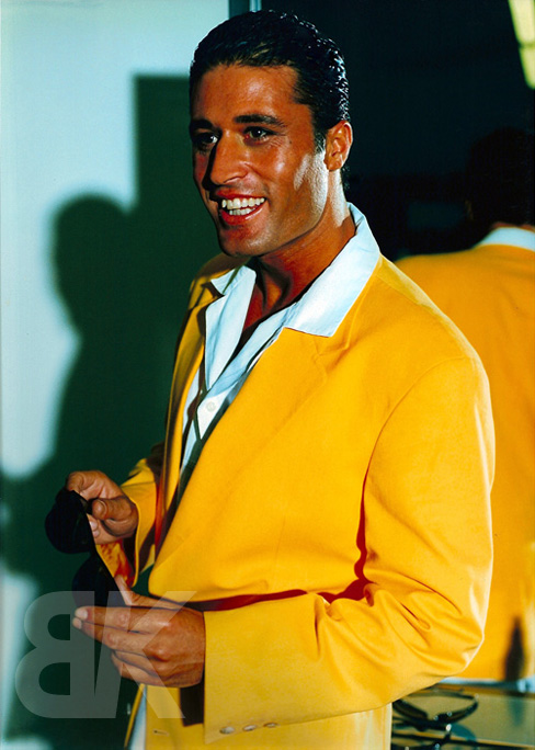 Bashkim Shala mit gelbem Sakko und Sonnenbrille in der Hand